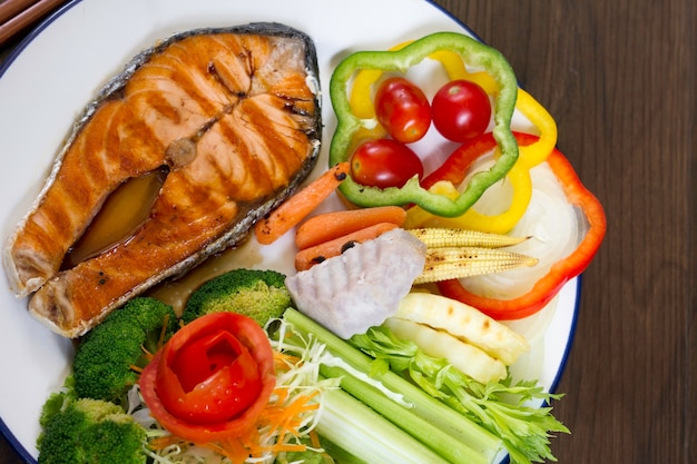 Salmon steak in a white plate on a wooden table.