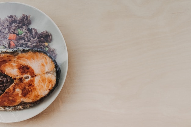 Salmon steak with fried rice on the dish and sealed with plastic