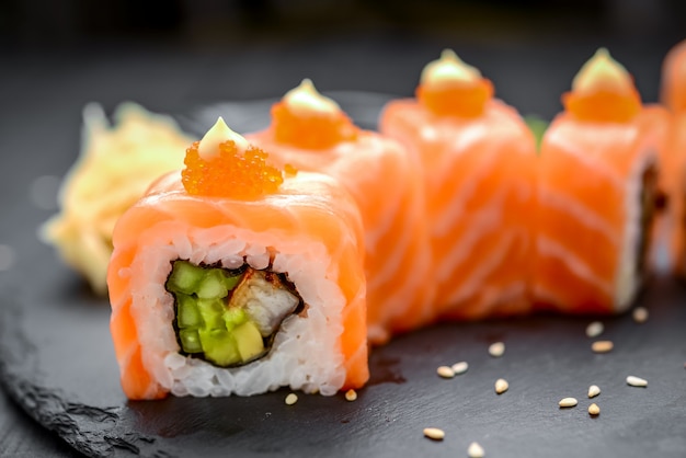 Salmon sushi rolls on black.