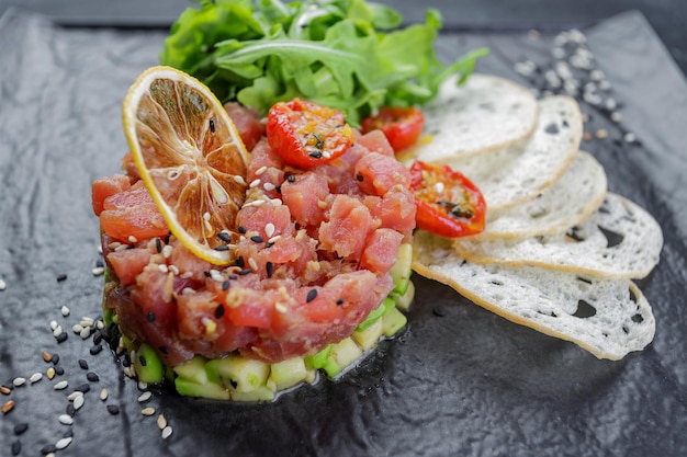 Salmon tartar with avocado on a black background