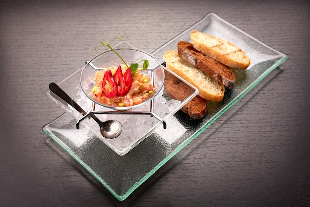 Salmon tartare in a glass dish on ice