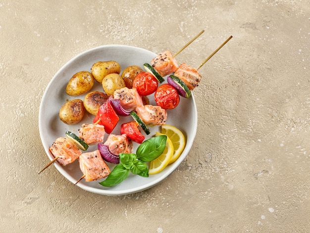 Salmon and vegetable skewers with roasted potatoes on restaurant table top view