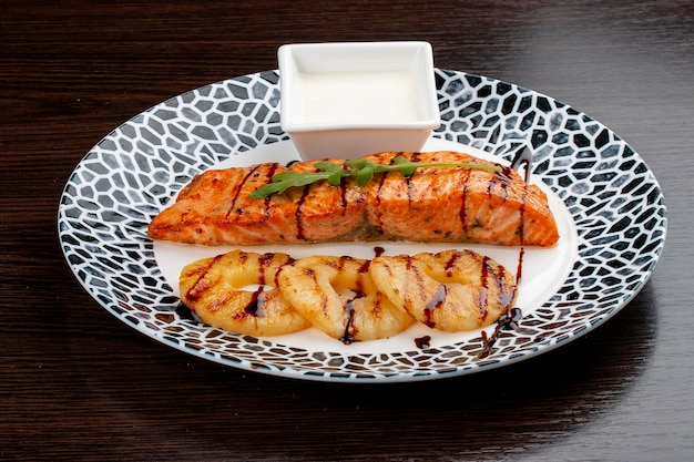 Salmon with cream sauce and grilled pineapple On a wooden background