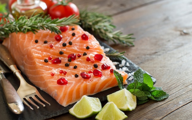 Salmon with vegetables and herbs on wooden table