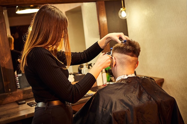 理髪店の椅子に座っているサロンマン美容師は理髪店のクライアントにサービスを提供します男性の美容の概念