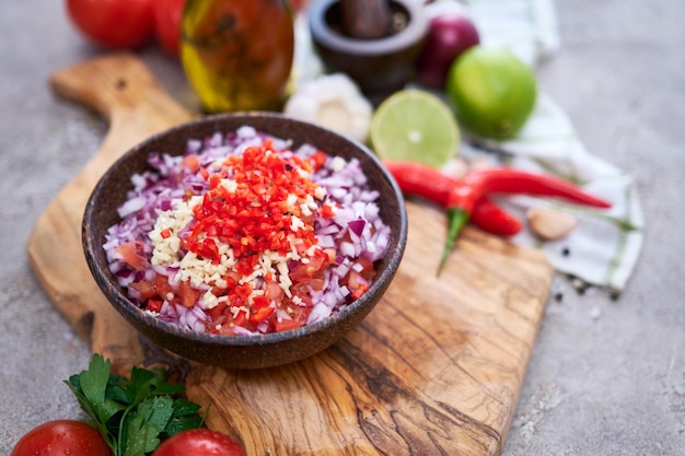 Salsa dipsaus maken gehakte knoflooktomaten en ui in houten kom