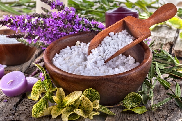 Bagno di sale in una ciotola di legno con fiori e foglie sullo sfondo