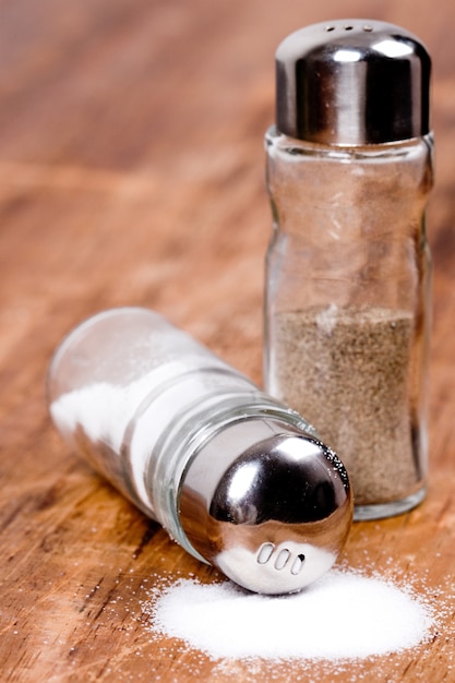 Photo salt and black pepper in shakers closeup on wooden background