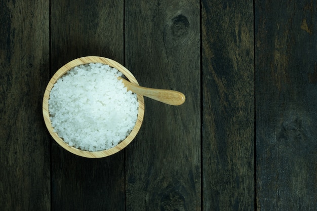 Salt in a bowl and spoon on wood background