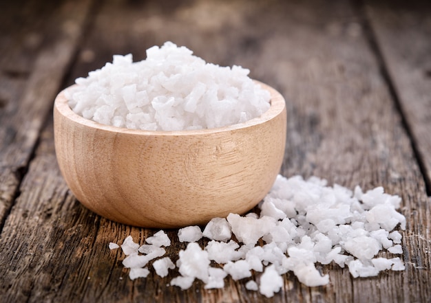 Salt in bowl on wooden background