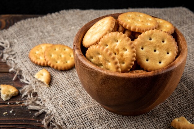 Salt crackers in wooden bowl on wooden background.