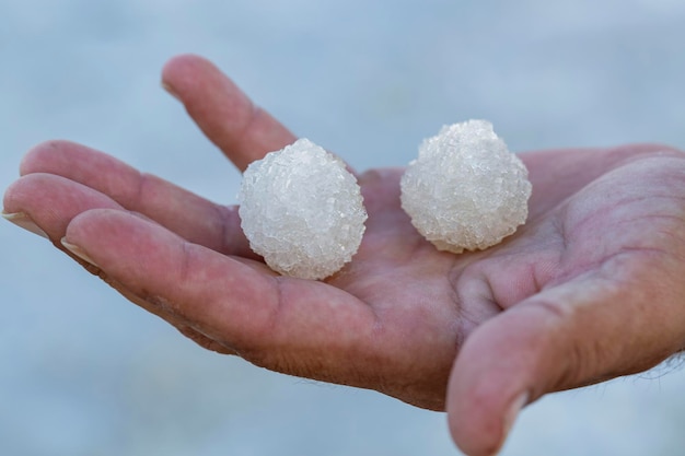 Salt crystals in the palms of your hands close up round cubes Shallow depth of field macro of white crystals of rock sea salt Salt from the Dead Sea on the palm of hand Crystallised Seasalt