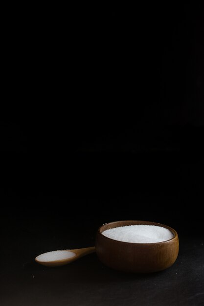 Salt in Cup made of wood with spoon  isolate on Black background