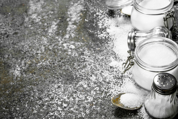 Salt in jars and spoons. On rustic table.