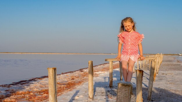 Salt Lake zit een meisje op een houten stok in een rode rok en glimlacht