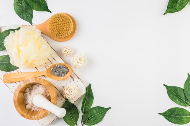 Salt; loofah; brush and leaves on white background