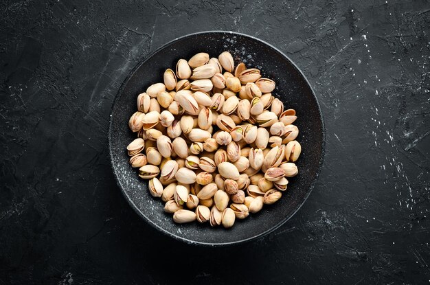 Salt pistachios in a bowl on a black background Top view Free space for your text