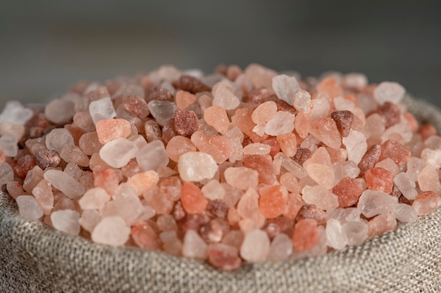 塩の価格ピンクのヒマラヤの塩のクローズアップの大きな結晶価格の上昇の象徴としての塩の山の中のコイン