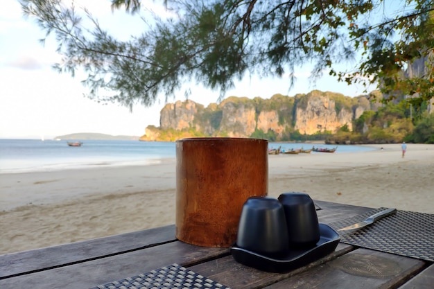 Salt shaker pepper shaker and napkins on wooden table on sandy shore of tropical island near sea