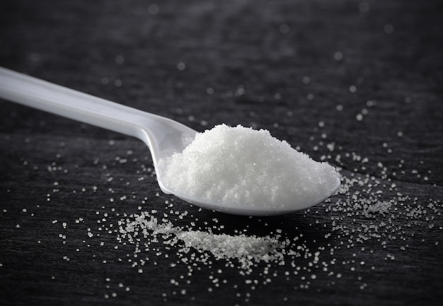 Salt in spoon on black wood