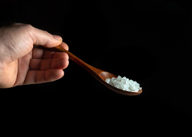 Соль или сахар в деревянной винтажной ложке в руке человека