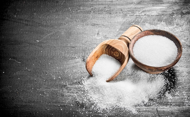 Salt in a wooden bowl. On the black chalkboard.