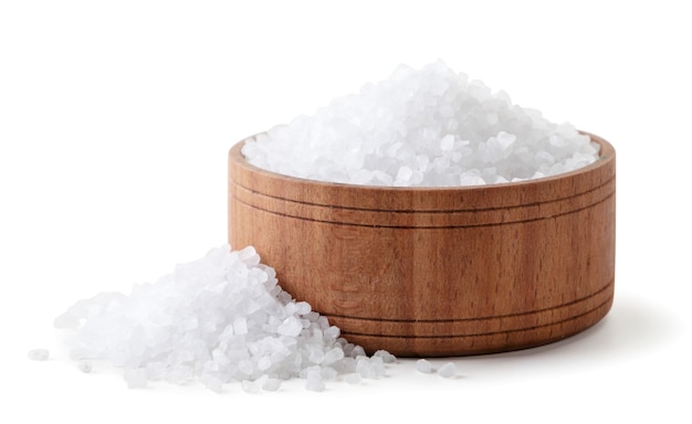 Salt in a wooden plate and sprinkled close-up on a white background. Isolated