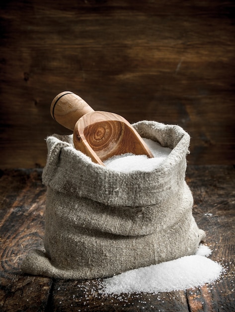 Salt in a wooden spoon. On wooden table.