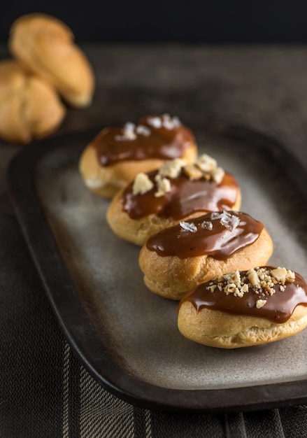 Photo salted caramel eclairs plated in a dark mood.