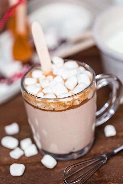 Cucchiaio di cioccolata calda al caramello salato in tazza di vetro condita con marshmallow.