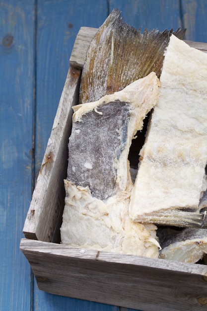 Salted cod fish in wooden box on blue wooden background