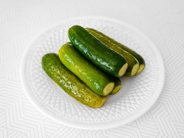 Salted cucumbers on a white plate on the table