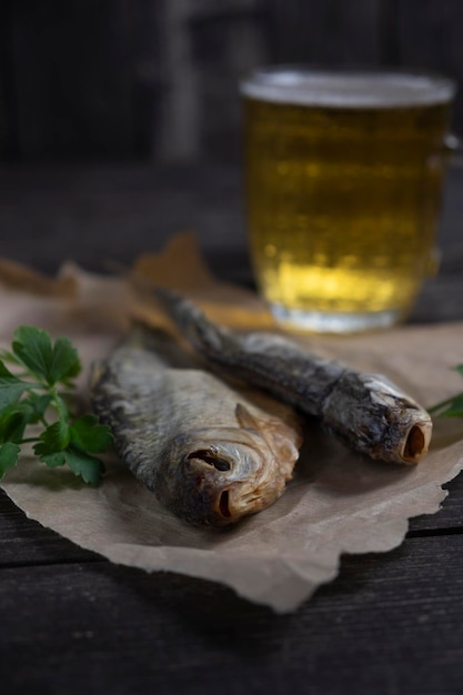 Salted dried vobla fish with amber beer on a dark wooden background with bread on the table selective focus
