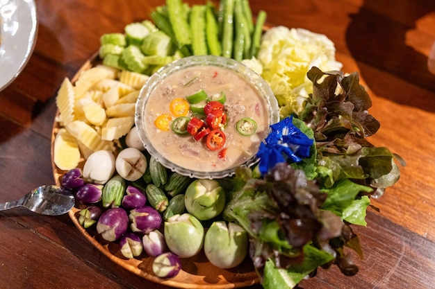 Salsa di pesce salata con erbe tailandesi e verdure mescolate su vassoio di legno