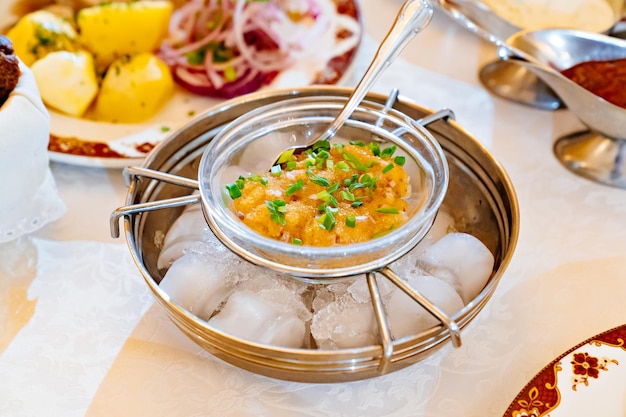 얼음과 함께 특별한 금속 접시에 파와 소금에 절인 생선 알. 냉각기구. 테이블 세팅. 안전한 음식 서빙.
