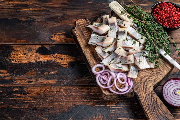 Salted herring fish sliced fillet on a wooden board with thyme