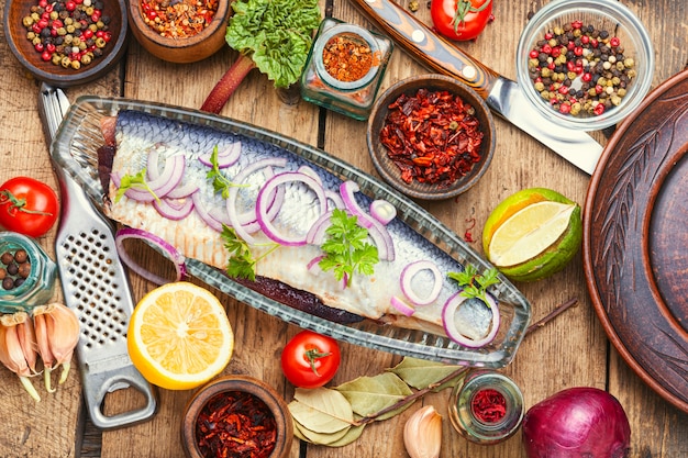 Salted herring with red onion on old wooden background.Rustic food