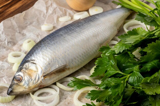 Salted herring on a wooden table with onion and parsley