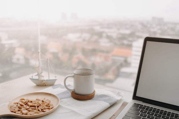 Salted peanuts black coffee and laptop on the desk