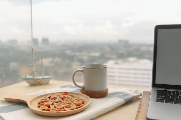 Arachidi salate caffè nero e laptop sulla scrivania