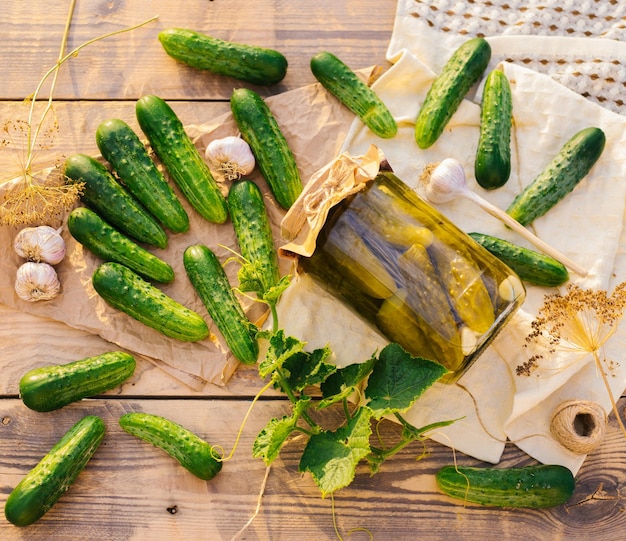 Salted pickled cucumbers in a jar on a wooden table in the garden Cucumbers herbs dill garlic Preservation conservation Background copy spaceTop view