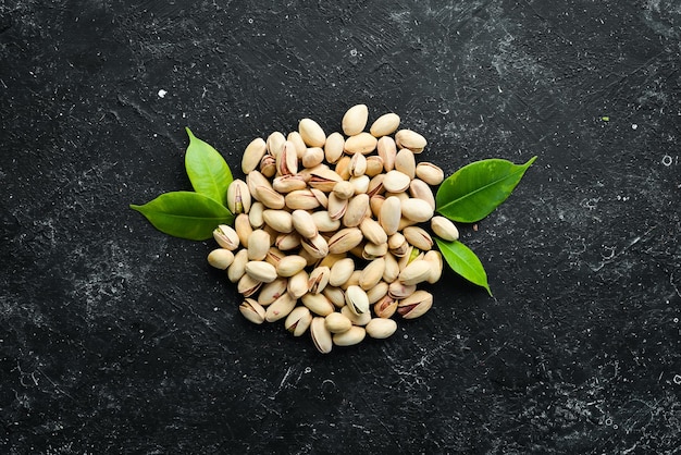 Salted pistachios on a black stone background free space for your text Top view