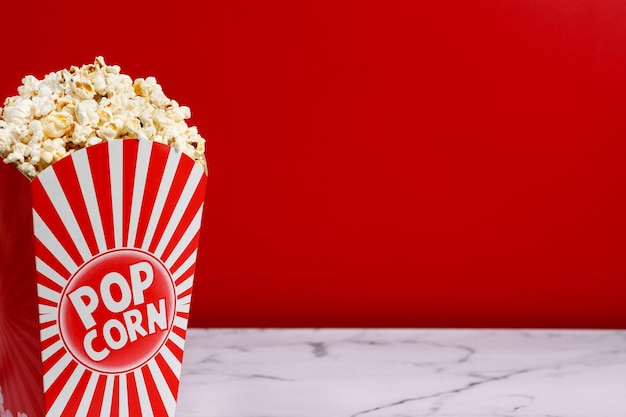 Salted popcorn scattered on white marble and red background