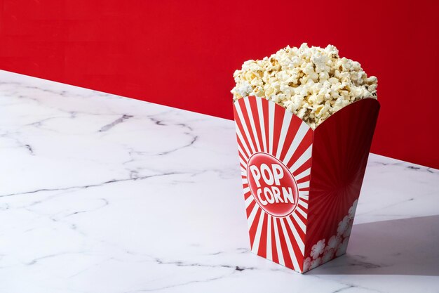 Salted popcorn on white marble and red background