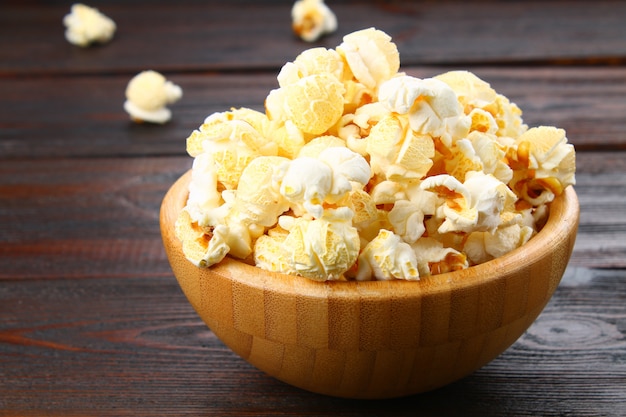 Salted popcorn in a wooden bowl on a wooden table.