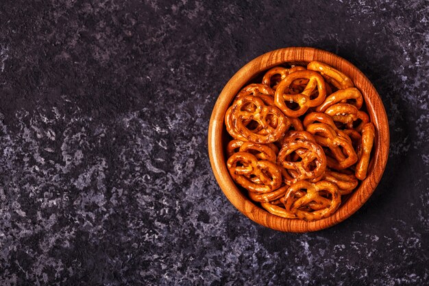 Salted pretzel in a bowl on stone background