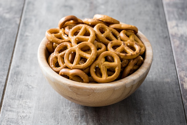 Salted pretzels in bowl on wooden background