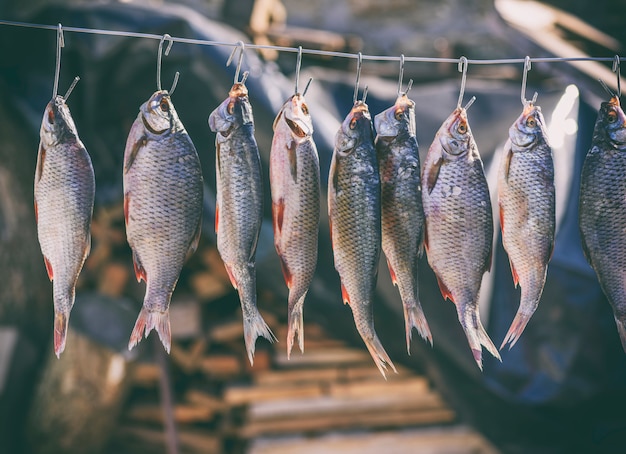 Salted river fish hanging on metal hooks 