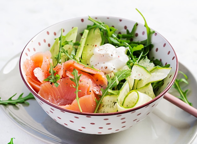 Salted salmon, avocado and cucumber salad with cream cheese in white bowl