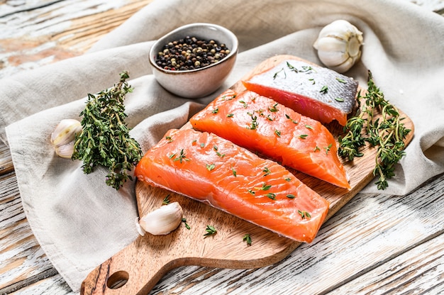 Salted salmon fillet with thyme on white wood. Top view